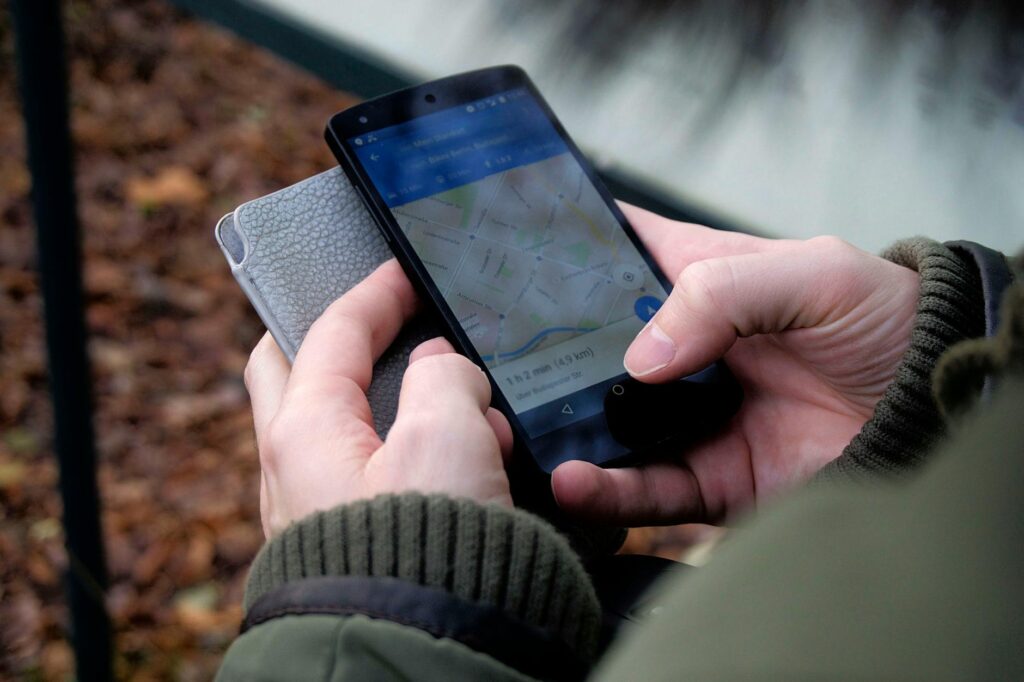 Close-up of hands using a map app on a smartphone outdoors, showcasing GPS navigation. (Photo by Ingo Joseph on Pexels)