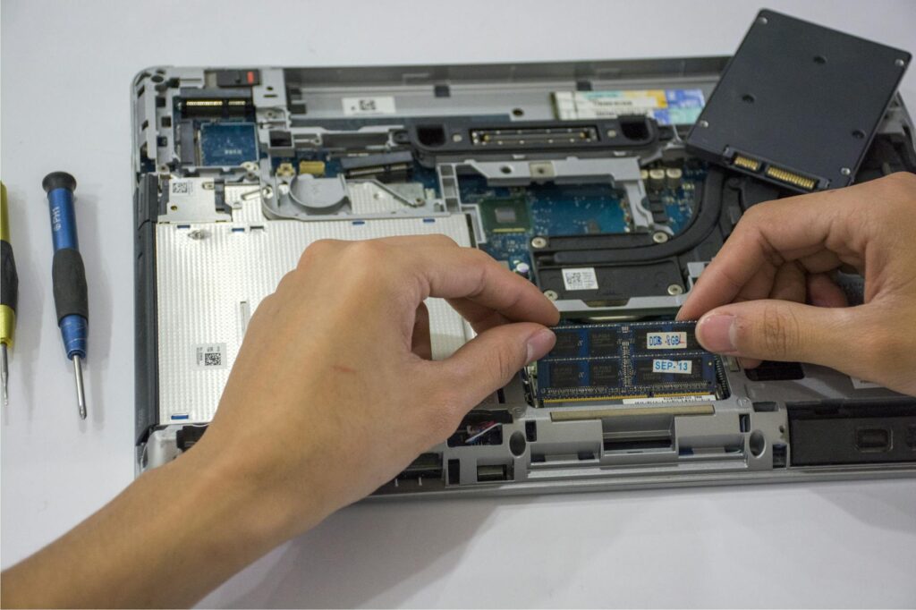 Close-up of a technician assembling a laptop's internal components using tools. (Photo by Elias Gamez on Pexels)