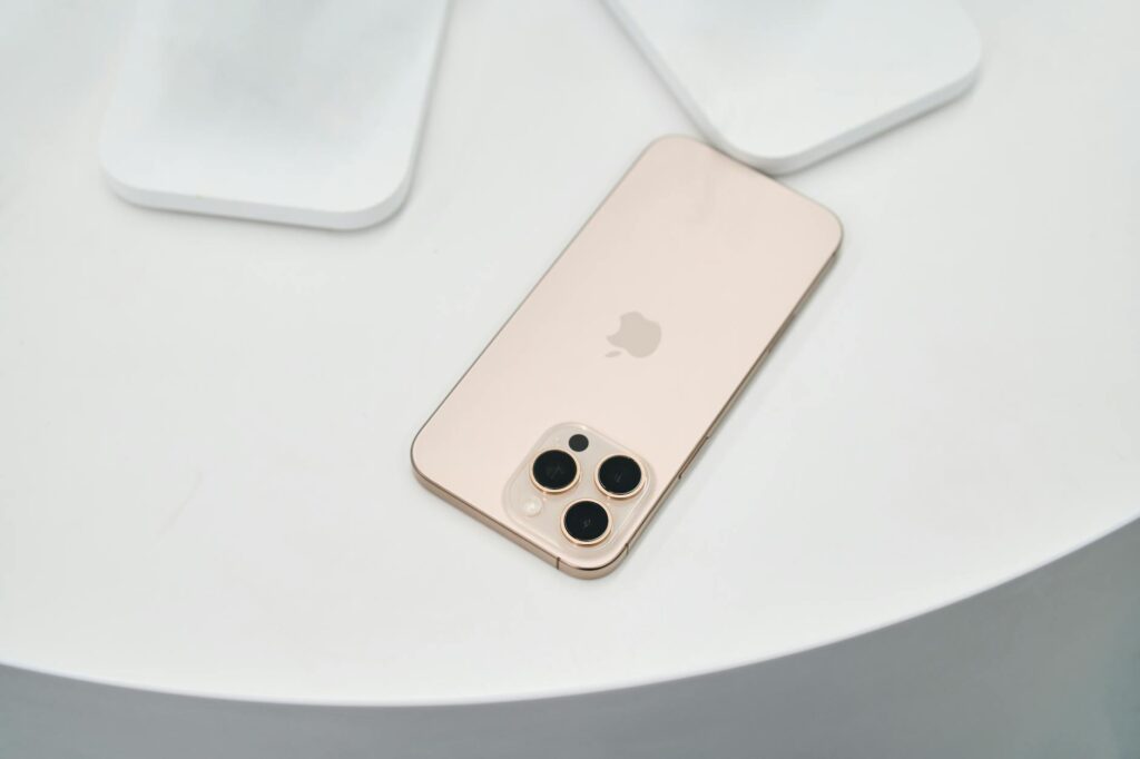 Golden smartphone with triple camera on a clean white surface. Modern design. (Photo by webber Amir on Pexels)
