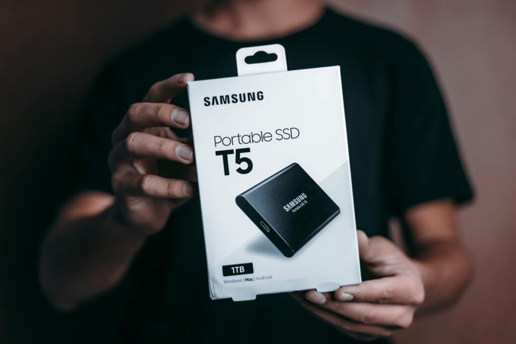 Close-up of a person holding a Samsung T5 Portable SSD box, emphasizing modern technology. (Photo by Luis Quintero on Pexels)
