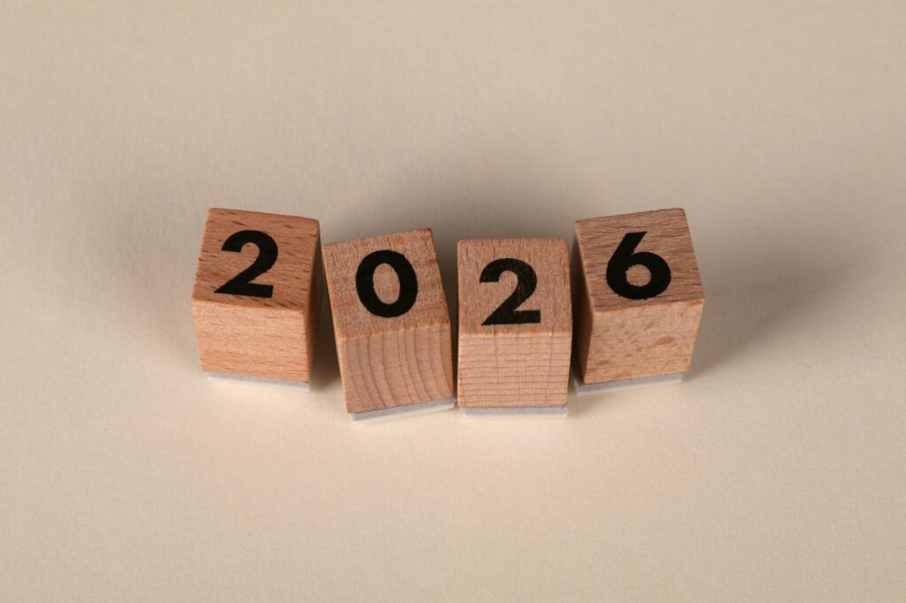 Wooden cubes forming the year 2026 on a neutral background. (Photo by Ann H on Pexels)