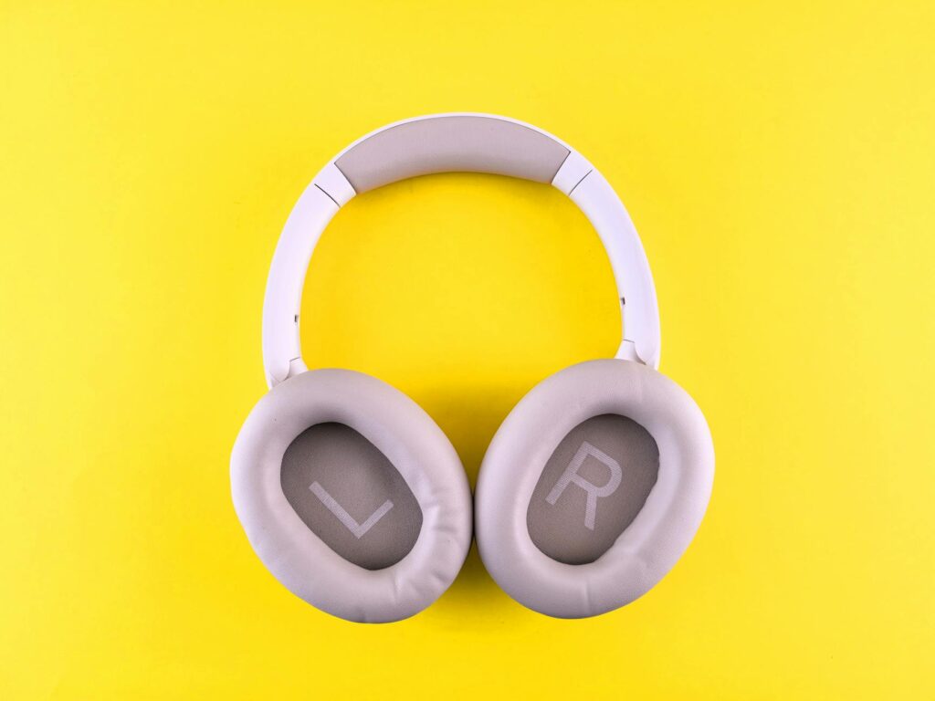 Stylish wireless headphones placed on a bold yellow surface, showcasing modern design and comfort. (Photo by Andrey Matveev on Pexels)
