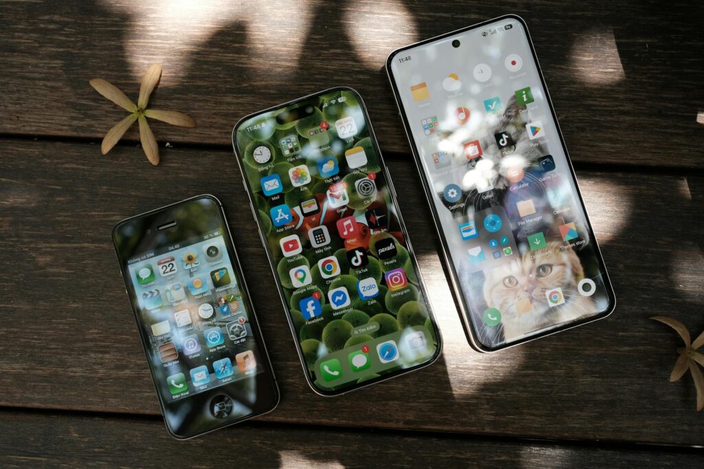 A collection of smartphones showing different app icons, placed on a wooden surface in natural li... (Photo by Phong Thanh on Pexels)
