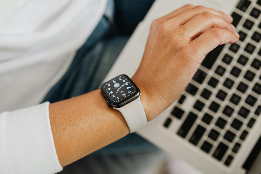 A person wearing a smartwatch working on a laptop, showcasing modern technology integration. (Photo by www.kaboompics.com on Pexels)