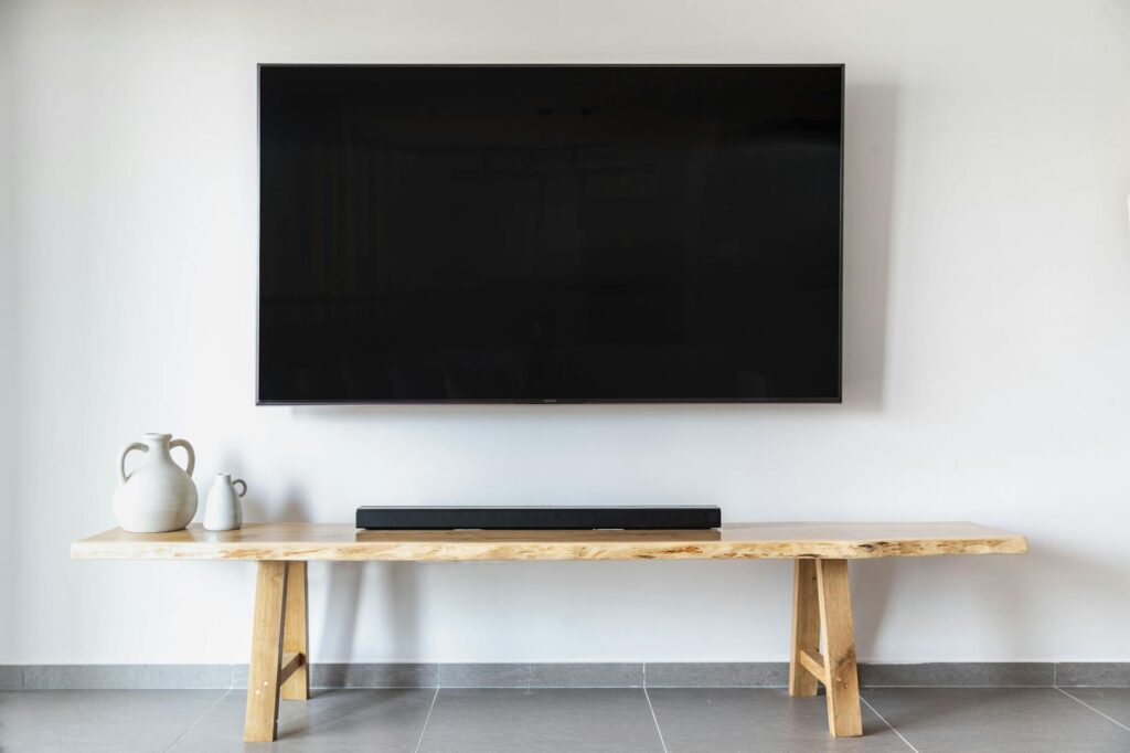 Stylish minimalist living room featuring a wall-mounted flat screen TV and wooden console. (Photo by yair elgazar on Pexels)