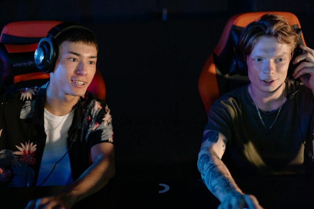 Two young men focused on an intense gaming session in a dark room, participating in a team esport... (Photo by Yan Krukau on Pexels)